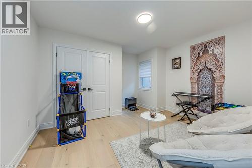 Spacious room featuring light wood-finish flooring, white walls, and a contemporary flush-mount ceiling light - 3937 Leonardo Street, Burlington, ON - Indoor