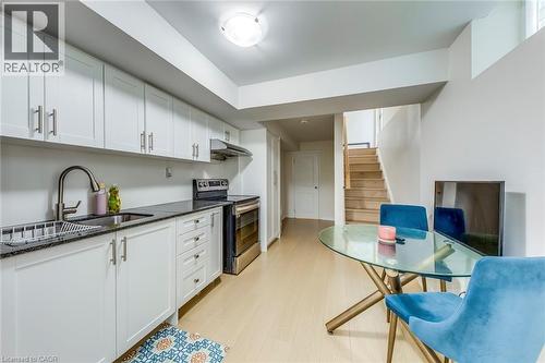 Kitchen with white shaker cabinetry, stainless steel appliances, dark stone-finish countertops, and light wood-finish flooring - 3937 Leonardo Street, Burlington, ON - Indoor Photo Showing Kitchen
