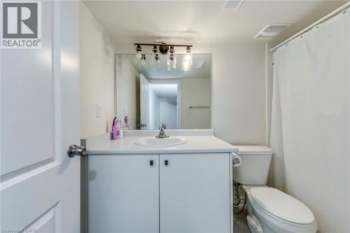 Bathroom featuring a white vanity with integrated sink, chrome faucet, a wall-mounted mirror, and industrial-style vanity lighting - 3937 Leonardo Street, Burlington, ON - Indoor Photo Showing Bathroom
