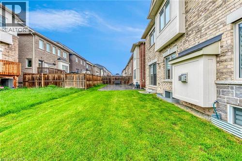 Expansive rear yard featuring green lawn, a stone patio, and wood fencing - 3937 Leonardo Street, Burlington, ON - Outdoor With Exterior
