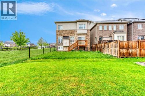 Expansive grassy backyard featuring a chain-link fence bordering a green space, a multi-level wood deck, and a brick and stucco exterior - 3937 Leonardo Street, Burlington, ON - Outdoor
