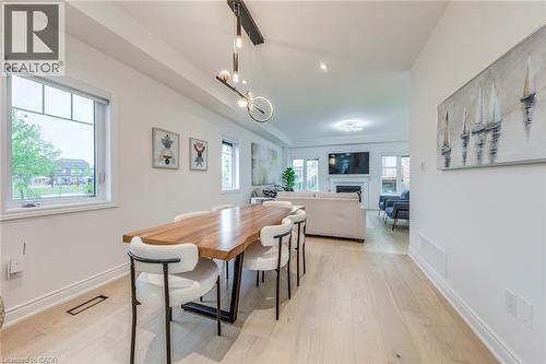Open-concept dining area featuring light wood-finish flooring, a contemporary linear chandelier, and ample natural light from multiple windows - 3937 Leonardo Street, Burlington, ON - Indoor Photo Showing Dining Room