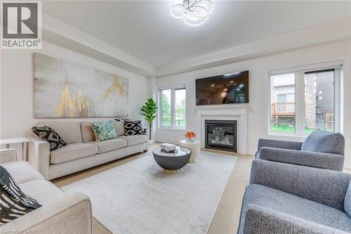 Spacious living area featuring light wood-finish flooring and a central fireplace with a classic mantel - 3937 Leonardo Street, Burlington, ON - Indoor Photo Showing Living Room With Fireplace