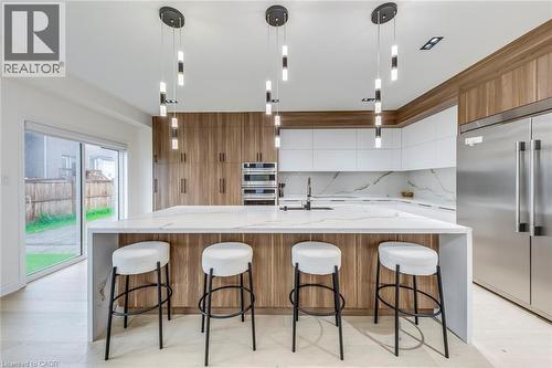 Gourmet kitchen with a waterfall island, integrated stainless steel appliances, wood-finish cabinetry, and contemporary pendant lighting - 3937 Leonardo Street, Burlington, ON - Indoor Photo Showing Kitchen With Upgraded Kitchen