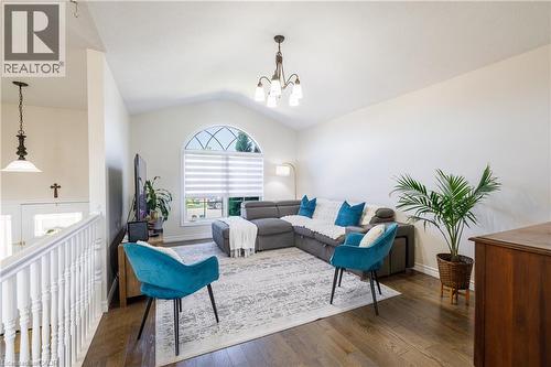 Living area featuring wood-finish flooring, a vaulted ceiling, and an arched window with decorative mullions - 10 Redbud Crescent, Simcoe, ON - Indoor Photo Showing Living Room
