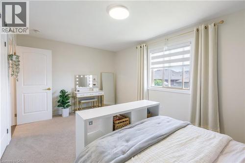 Carpeted room featuring a window with horizontal blinds and curtains, a white paneled door, and a flush-mount ceiling light - 10 Redbud Crescent, Simcoe, ON - Indoor Photo Showing Bedroom