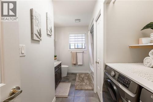 Compact laundry area featuring a front-loading washing machine, countertop space, and floating shelf - 10 Redbud Crescent, Simcoe, ON - Indoor Photo Showing Laundry Room