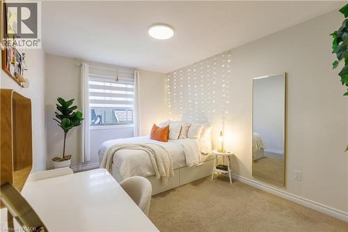 Carpeted bedroom with neutral wall tones and a single window featuring horizontal blinds and white drapes - 10 Redbud Crescent, Simcoe, ON - Indoor Photo Showing Bedroom