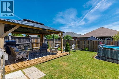 Expansive backyard featuring a natural wood-finish deck with a built-in gazebo, a manicured lawn, and a privacy fence - 10 Redbud Crescent, Simcoe, ON - Outdoor With Above Ground Pool With Deck Patio Veranda
