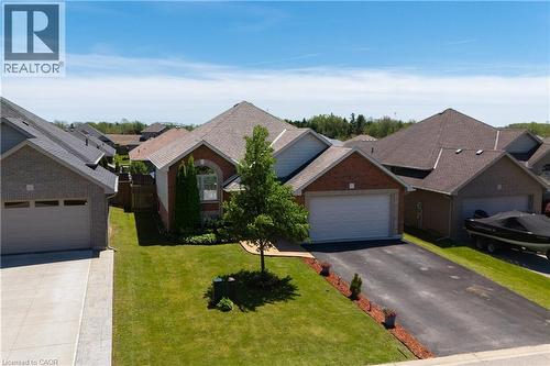 Brick exterior residence featuring an attached garage, paved driveway, and manicured front lawn - 10 Redbud Crescent, Simcoe, ON - Outdoor With Facade