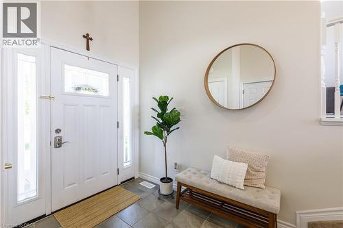 Entryway featuring a white paneled door with glass sidelights and transom window, gray tile flooring, and a circular wall mirror with a wooden frame - 10 Redbud Crescent, Simcoe, ON - Indoor Photo Showing Other Room