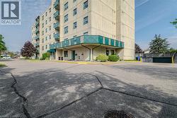 Multi-story condominium building featuring a light-colored stucco exterior with green balcony railings and a covered entrance - 
