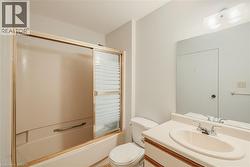 Bathroom featuring a built-in tub with sliding shower doors, a single-basin vanity, and a wall-mounted mirror - 
