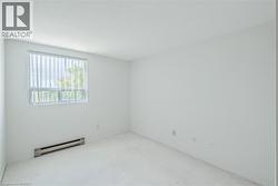 Bright room featuring a window with vertical blinds, white walls, and light-colored carpeting - 