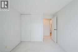 Bright interior space featuring light-colored carpeting, white painted walls, and a white ceiling - 