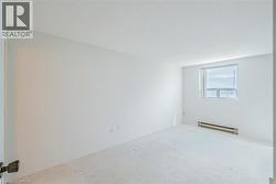 Bright room featuring a single window, baseboard heating, carpeted flooring, and white painted walls - 