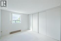 Bright room featuring a window with white trim, white walls, and light-colored carpet flooring - 