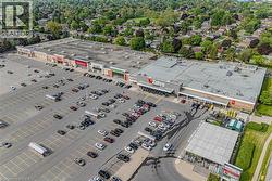 Large commercial plaza featuring multiple retail storefronts and an expansive paved parking lot - 