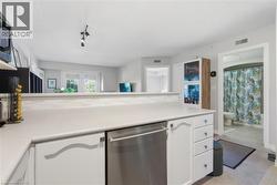 Kitchen countertop with integrated dishwasher, white cabinetry, and a textured backsplash - 