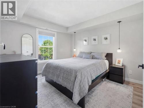 Bedroom featuring light-colored carpet, a ceiling pendant light, and white paneled bi-fold closet doors - 1421 Walkers Line Unit# 209, Burlington, ON - Indoor Photo Showing Bedroom