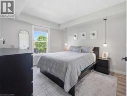 Recessed ceiling with an overhead light fixture, large window, and wood-finish flooring - 
