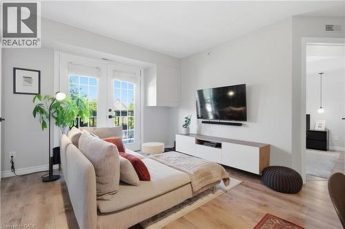 Recessed ceiling with an overhead light fixture, large window, and wood-finish flooring - 1421 Walkers Line Unit# 209, Burlington, ON - Indoor Photo Showing Bedroom