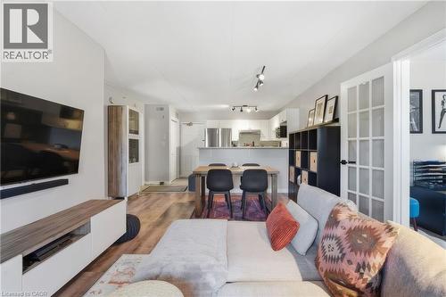 Open-concept living space featuring wood-finish flooring, recessed lighting, and a white entertainment console - 1421 Walkers Line Unit# 209, Burlington, ON - Indoor Photo Showing Living Room