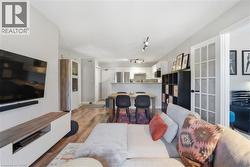 Open-concept living space featuring wood-finish flooring, recessed lighting, a built-in media console, and French doors - 