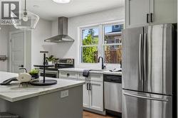 Contemporary kitchen featuring stainless steel appliances, light gray cabinetry, and stone countertops - 