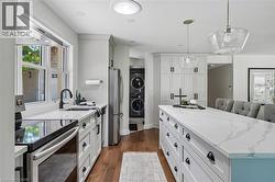 Modern kitchen featuring a large center island with integrated seating, white cabinetry, dark hardware, stainless steel appliances, and a skylight - 