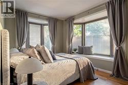 Bay window with integrated window seat, wood-finish flooring, painted walls, and ceiling-mounted light fixture - 