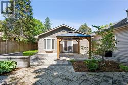 Paved patio area featuring a wooden gazebo with a dark roof and access to interior space through sliding glass doors - 
