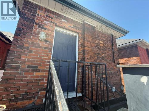 Brick exterior featuring a black entry door, metal handrail, and exterior lighting fixture - 359 Barton Street E Unit# Upper, Hamilton, ON - Outdoor With Exterior