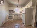 Kitchen featuring white cabinetry, a white refrigerator and range, a stainless steel sink, and light-toned tile flooring - 359 Barton Street E Unit# Upper, Hamilton, ON  - Indoor Photo Showing Kitchen With Double Sink 