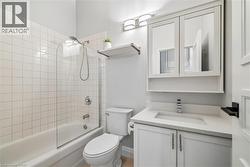 Full bathroom featuring a white subway tile surround, clear glass shower panel, white vanity with integrated sink, and a wall-mounted medicine cabinet - 