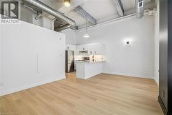 Open-concept living space featuring wood-finish flooring, exposed ductwork, and high ceilings - 