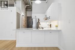 Modern kitchen featuring white cabinetry with matte black hardware, a quartz-look countertop, a subway tile backsplash, and stainless steel appliances - 