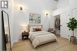 Bedroom featuring light wood-finish flooring, white walls, and a built-in closet with panel doors - 