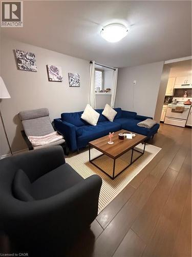 Living area featuring wood-finish flooring, a flush-mount ceiling light fixture, and a built-in kitchen visible beyond an archway - 947 Main Street E Unit# 6, Hamilton, ON - Indoor