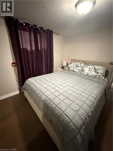 Bedroom featuring wood-finish flooring, a contemporary flush-mount ceiling light, and deep-toned window treatments - 947 Main Street E Unit# 6, Hamilton, ON - Indoor Photo Showing Bedroom