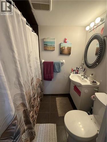 Bathroom featuring a wall-mounted vanity with integrated sink, a commode, and a shower area - 947 Main Street E Unit# 6, Hamilton, ON - Indoor Photo Showing Bathroom