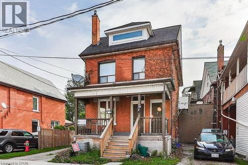 Brick exterior featuring a covered front porch with wood railings and steps - 10 Fairleigh Avenue N, Hamilton, ON - Outdoor With Deck Patio Veranda