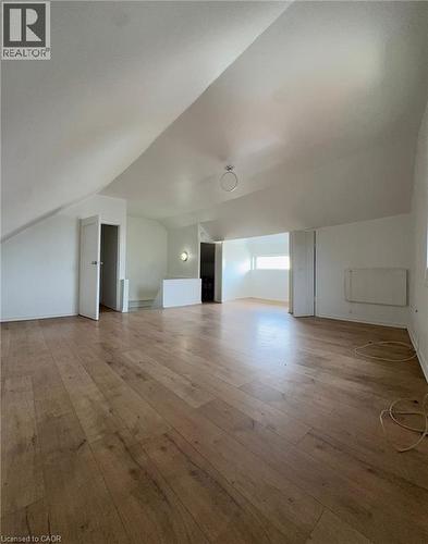 Spacious attic room featuring wood-finish flooring, white walls, and a sloped ceiling - 10 Fairleigh Avenue N, Hamilton, ON - Indoor Photo Showing Other Room