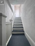 Stairwell featuring painted white risers and dark treads, white balusters, and textured wall finishes - 