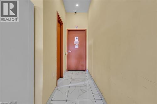 Hallway with light beige walls and white-patterned floor tiles - 5 Manitou Drive Unit# 106B, Kitchener, ON 