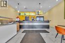 Commercial counter space featuring a dark wood-finish facade with a light gray stripe, a black countertop, and multiple wall-mounted display screens - 5 Manitou Drive Unit# 106B, Kitchener, ON 