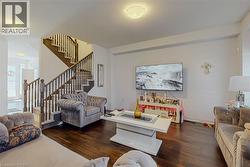 Spacious room featuring rich wood-finish flooring and a multi-level staircase with wood balusters - 