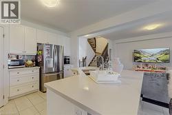 Kitchen featuring white cabinetry, stainless steel appliances, a center island with sink, and light-toned countertops - 