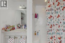 Bathroom featuring a single vanity with an oval sink, a light-toned countertop, and white cabinetry - 