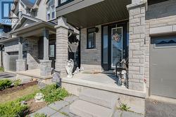 Stone facade with covered front porch, featuring a dark-framed entry door with clear glass panels - 
